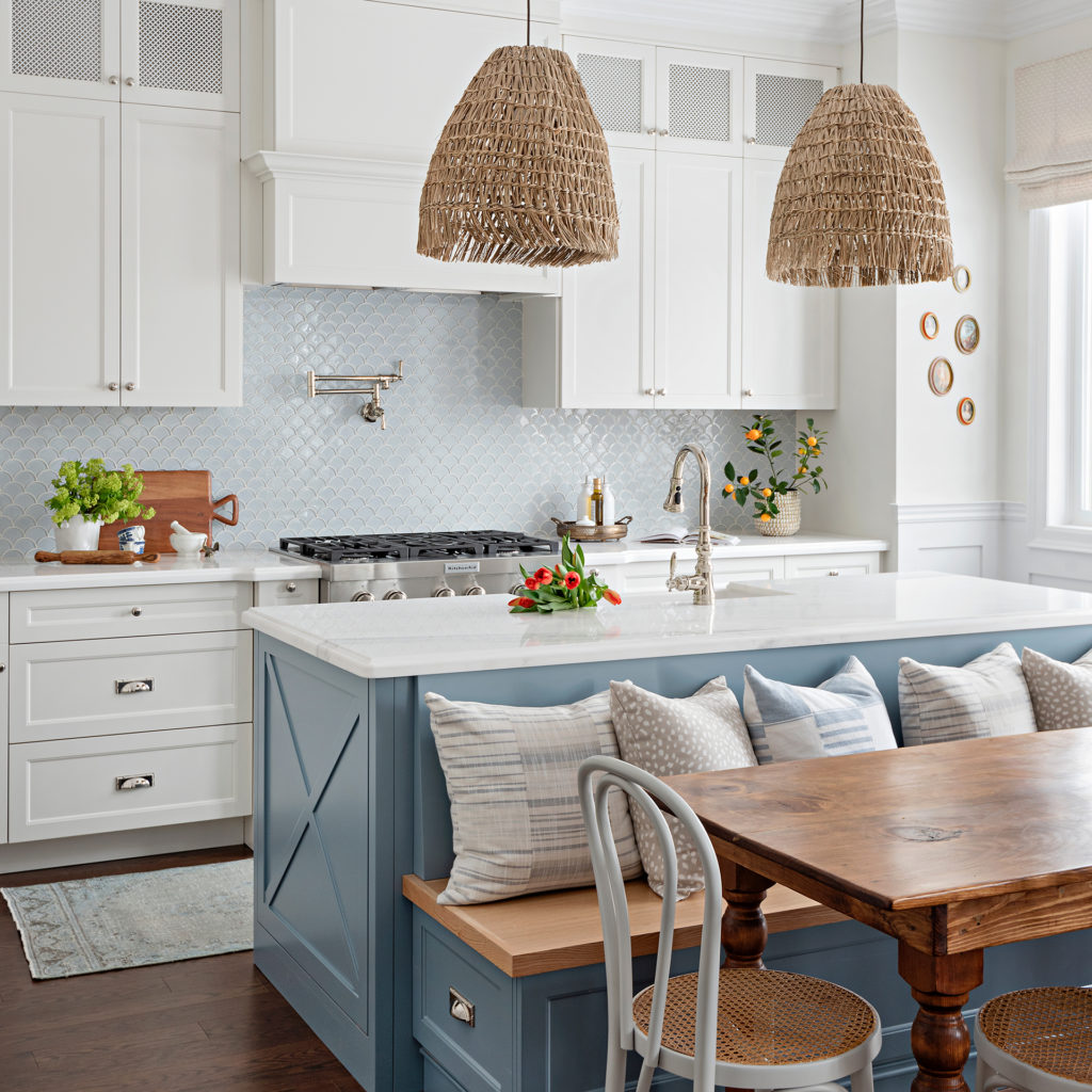 The kitchen with a blue island and banquette, and natural elements such as woven pendant lamps.