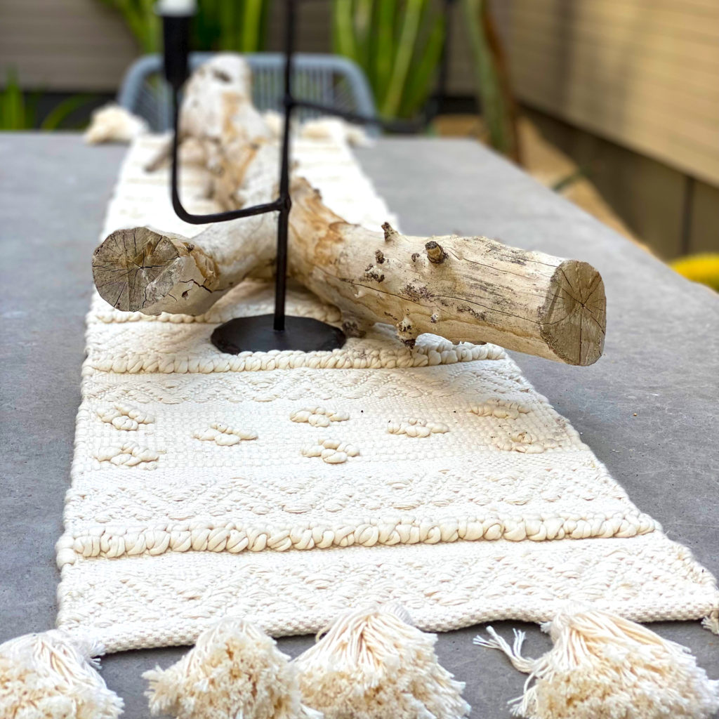 A dining table with driftwood and a natural runner